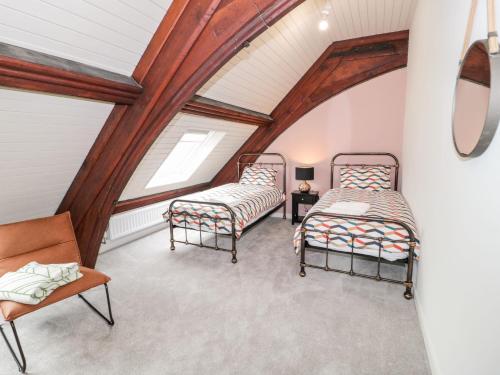 a attic room with two beds and a chair at Salem in Prestatyn