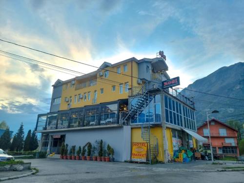 un edificio blanco y amarillo con una escalera. en Hotel Rosi en Gusinje