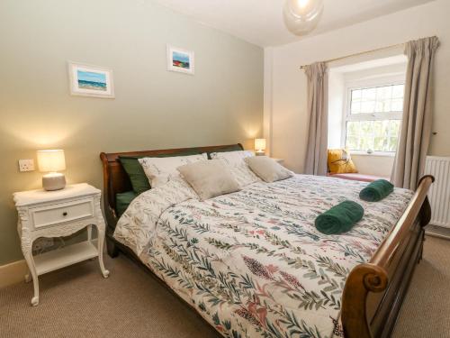 a bedroom with a bed with a night stand and a window at Mill House Main House in Pwllheli