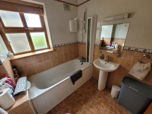 a bathroom with a bath tub and a sink at Roadside Cottage The Burren Kilfenora County Clare in Kilfenora