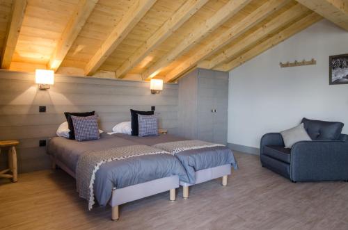 a bedroom with two beds and a chair at Chalets Residence Snoweden in Montchavin