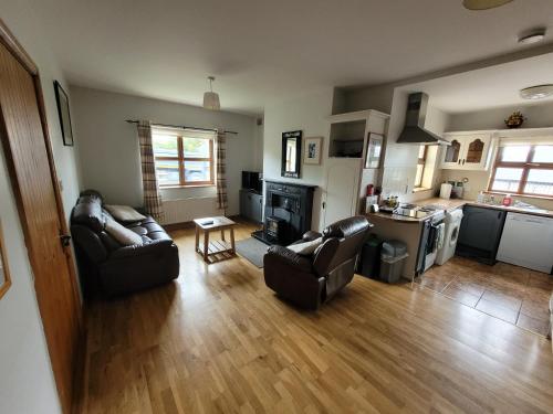 a living room with two leather chairs and a fireplace at Roadside Cottage The Burren in Kilfenora