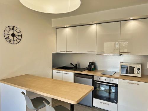 une cuisine avec des armoires blanches et une table avec un micro-ondes dans l'établissement T2 Centre ville avec parking gratuit, à Toulouse