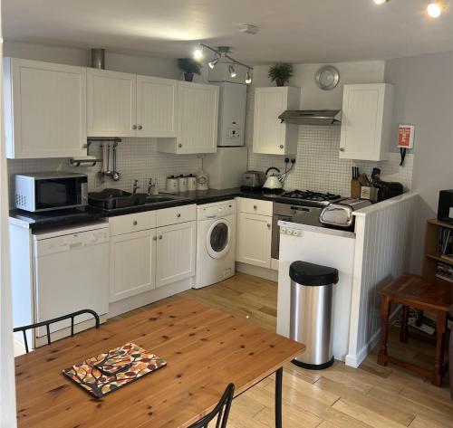 a kitchen with white cabinets and a wooden table at The Garden Apartment in Ironbridge