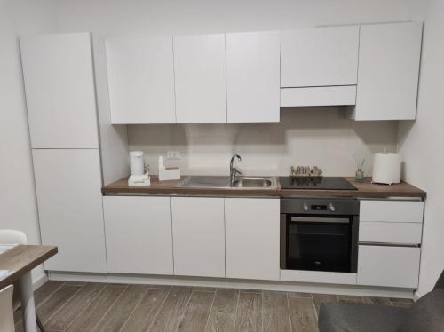 Una cocina con gabinetes blancos y un fregadero. en Kitros, en Palagiano