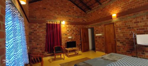a bedroom with a brick wall with a bed and a television at the motville in Pulpally