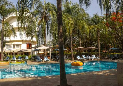 a pool with palm trees and chairs and a building at The Lorian Club in Cocoyoc