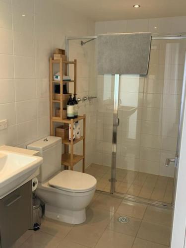a bathroom with a toilet and a shower and a sink at Spacious sun-drenched apartment, centrally located in Canberra