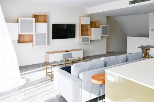 Spacious sun-drenched apartment, centrally located في كانبرا: غرفة معيشة مع أريكة وتلفزيون