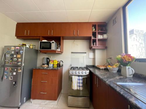 a kitchen with wooden cabinets and a stainless steel refrigerator at Private bedroom in Calacoto in La Paz