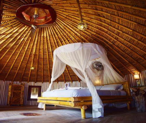 ein Schlafzimmer mit einem Bett in einer Strohhütte in der Unterkunft Meno Island Villas in Gili Meno