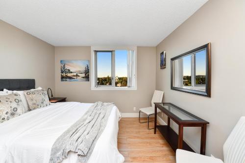 a bedroom with a bed and a desk and two windows at Harbour Walk Executive Condo in Victoria