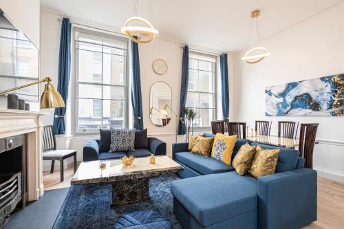 een woonkamer met blauwe banken en een open haard bij Spacious and Comfy 4 Bedroom House near Oxford Street and marble Arch in Londen