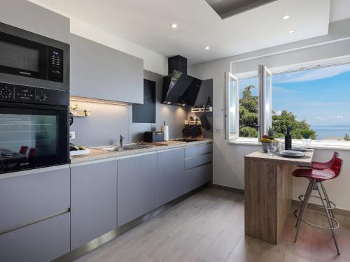 a kitchen with white cabinets and a large window at Apartment Rodela in Opatija