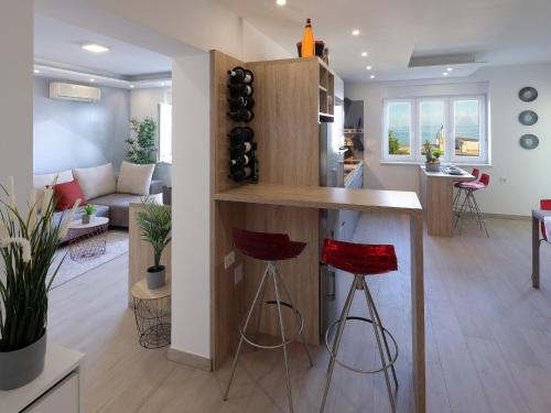 a kitchen and living room with a bar with red stools at Apartment Rodela in Opatija