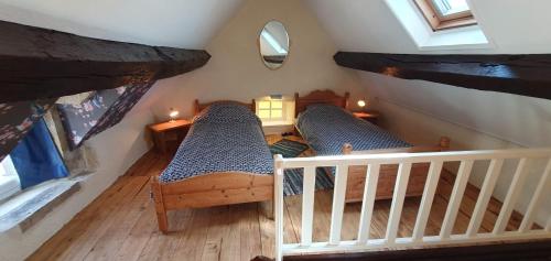 an attic room with two beds and a mirror at Le Fier Paon in Pierrefaites