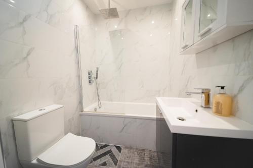 a white bathroom with a toilet and a sink at Star London Bell Lane 3-Bed Haven in Hendon