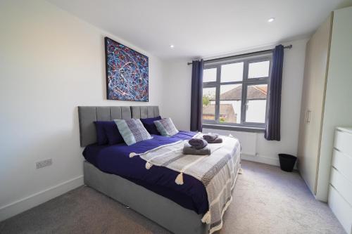 a bedroom with a bed with blue sheets and a window at Star London Bell Lane 3-Bed Haven in Hendon