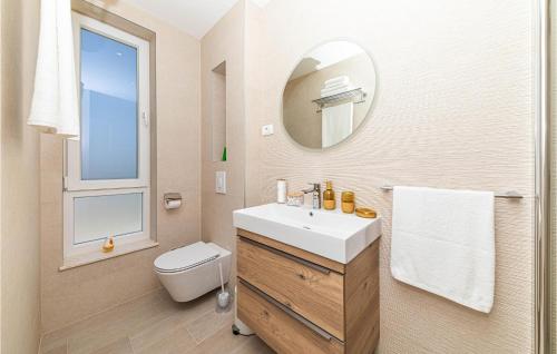 een badkamer met een wastafel, een toilet en een spiegel bij 4 Bedroom Amazing Home In Kastel Gomilica in Kaštela
