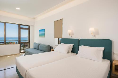 a bedroom with a white bed and a blue chair at Hermes Sea View in Stalos