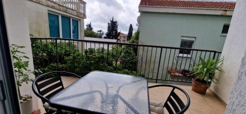 a glass table and chairs on a balcony with a balcony at Apartmani Komatina Đenovići 2 in Herceg-Novi
