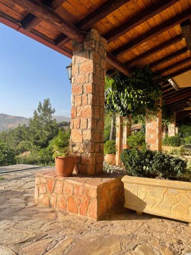 a stone porch with a wooden roof and plants at Aphrodite's Inn Kalavrita in Kalavrita