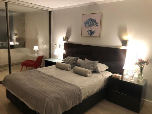 una camera da letto con un grande letto con due cuscini sopra di Apartamento Parque Arauco Kennedy a Santiago