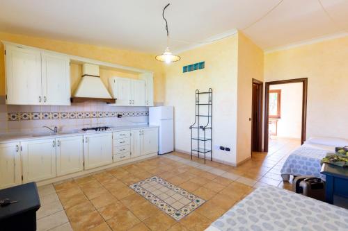 a large kitchen with white cabinets and a sink at Borgo Donna Canfora in Capo Vaticano