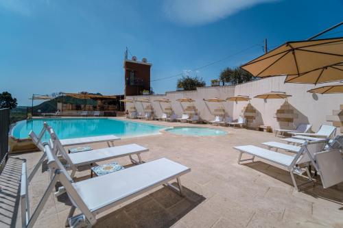uma piscina com cadeiras, mesas e guarda-sóis em Don Vittorio Country Village em Taormina