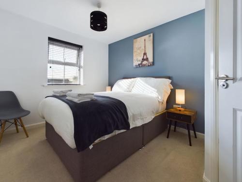 een slaapkamer met een groot bed met een blauwe muur bij 247 Serviced Accommodation in Stafford- 3BR Townhouse in Stafford