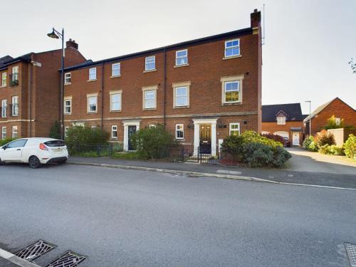 a white car parked in front of a brick building at 247 Serviced Accommodation in Stafford- 3BR Townhouse in Stafford