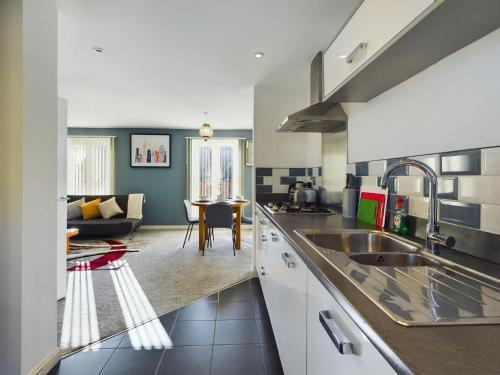 a kitchen with a sink and a living room at 247 Serviced Accommodation in Stafford- 3BR Townhouse in Stafford
