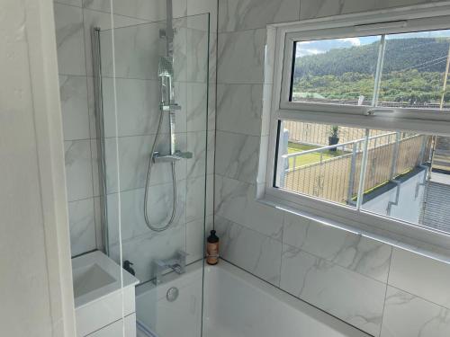 a white bathroom with a shower and a window at Prospect Cottage by StayStaycations in Treorky