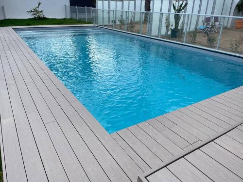 uma piscina com um deque de madeira ao lado de um edifício em Villa Pieds dans l’eau em Carry-le-Rouet