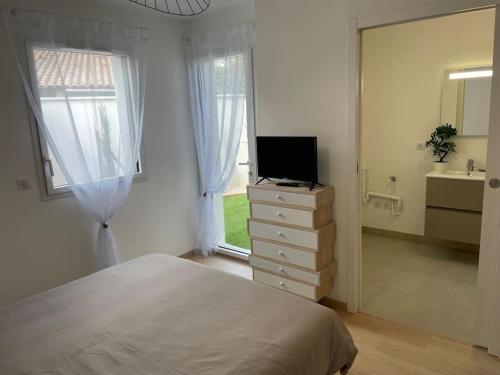 een slaapkamer met een bed en een televisie op een dressoir bij Villa Pieds dans l’eau in Carry-le-Rouet