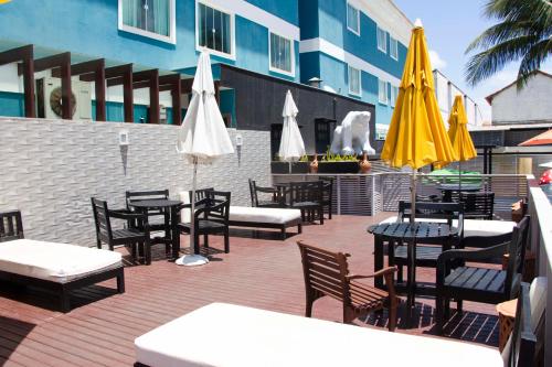 un patio extérieur avec des tables, des chaises et des parasols dans l'établissement Pousada SUN Victory, à Cabo Frio