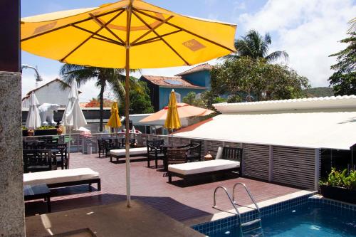 un ombrellone giallo seduto accanto alla piscina di Pousada SUN Victory a Cabo Frio