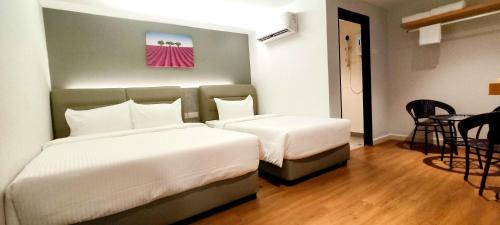 a hotel room with two beds and a table at MILAN HOTEL in Johor Bahru