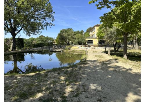 a house with a pond in front of a building at BASTIDE DU DEFENDS in Pertuis