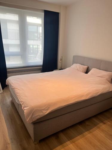 een groot bed in een slaapkamer met 2 ramen bij Portofino - luxe appartement met lateraal zeezicht in Oostende