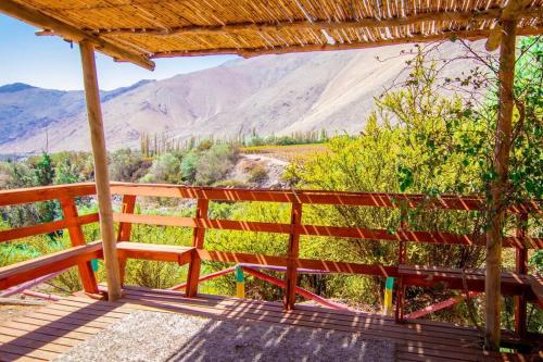 a wooden bench on a porch with mountains in the background at Cabaña La Casona de Ripaluna in Paihuano