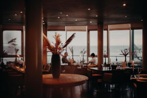 a restaurant with tables and chairs and a vase with plants at Strandhotel Ostseeblick in Heringsdorf