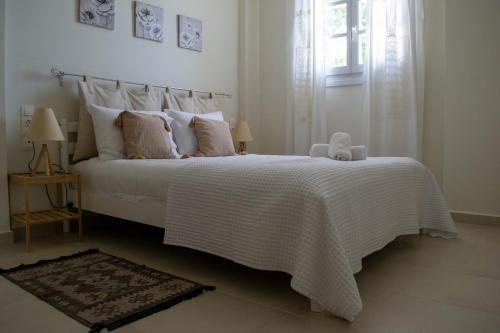 a bedroom with a bed with a white blanket and a window at Sea and Creek in Katelios
