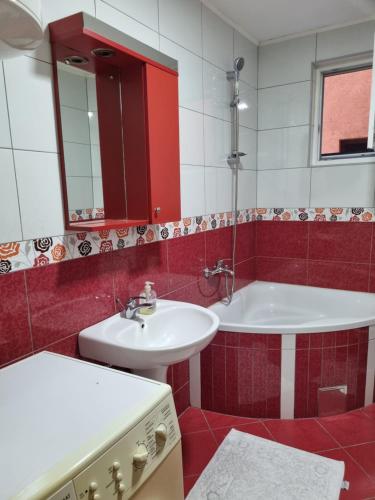uma casa de banho vermelha e branca com um lavatório e uma banheira em Apartman- Sarajevo em Sarajevo