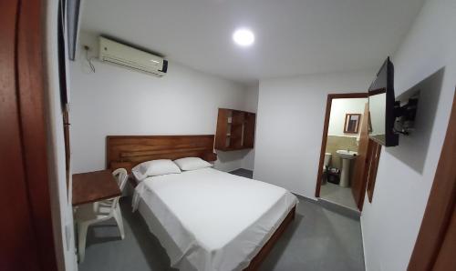 een slaapkamer met een wit bed en een spiegel bij HOTEL SAN ADOLFO in Apartadó