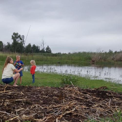 a woman and two children standing next to a lake at Diamantvallei Landgoed in Rayton