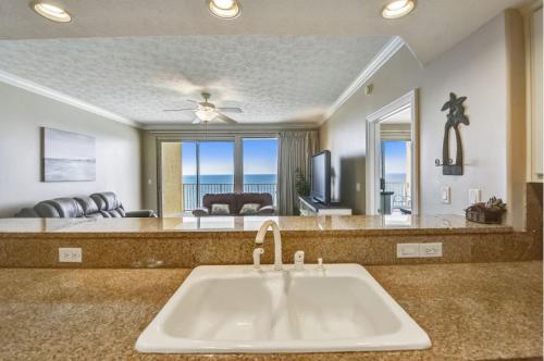 a bathroom with a sink and a living room at Treasure Island 2103 in Panama City Beach