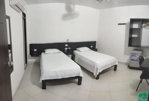 a room with two beds and a tv in it at HOTEL SAN ADOLFO in Apartadó
