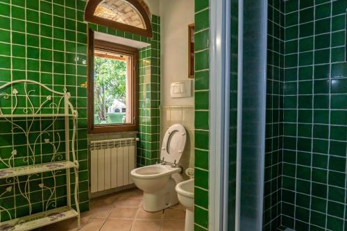 baño de azulejos verdes con aseo y ventana en MAREMMA TOSCANA [PISCINA & IDROMASSAGGIO], en Grosseto