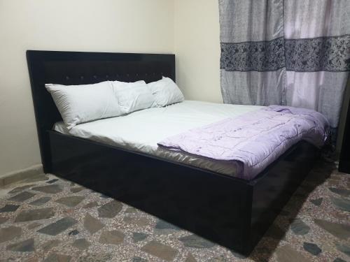 a bed with a black frame and white pillows on it at Joefad Home Stay - Wuse Zone 5 in Abuja